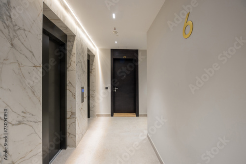 Interior of a corridor with apartment doors and marble wall