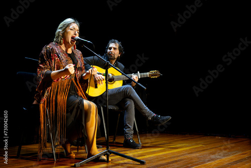 Emotive flamenco singer with accompanying guitarist on stage, copy space.