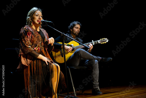 Flamenco duo in concert: singer and guitarist on wooden stage, copy space.