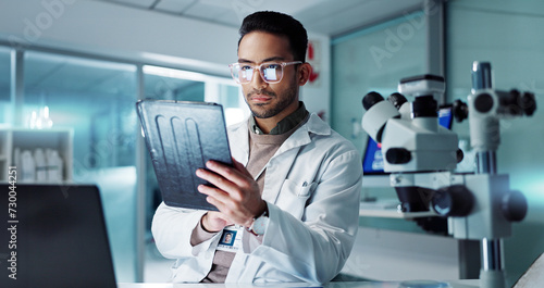 Tablet, scientist and reading for analysis in laboratory, healthcare and online pharmaceutical research . Asian expert, computer and microscope for medicine and information on innovation cure at work photo