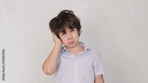 Boy holds his head, wincing from ear pain. A clear depiction for healthcare providers illustrating symptoms of otitis.
