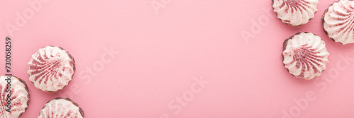 Beautiful white vanilla soft zephyrs with dry strawberry powder on light pink table background. Pastel color. Closeup. Sweet food wide banner. Empty place for text. Top down view.