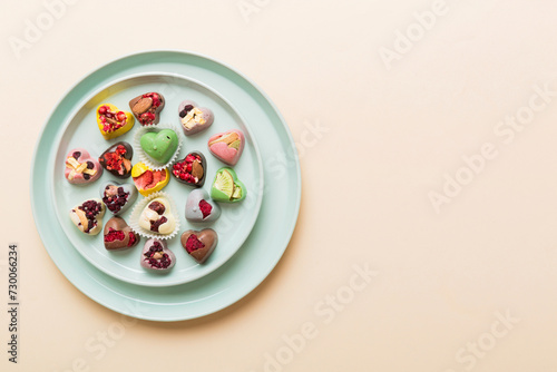 Plate with different chocolate on colored background. Assortment of fine chocolates top view vith copy space Health and obesity concept