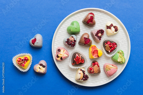 Plate with different chocolate on colored background. Assortment of fine chocolates top view vith copy space Health and obesity concept