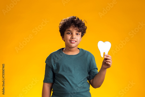Child boy holding papercraft tooth. Dental health concept photo
