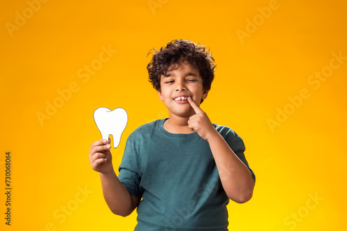 Child boy holding papercraft tooth and pointing finger at mouth. Dental health concept