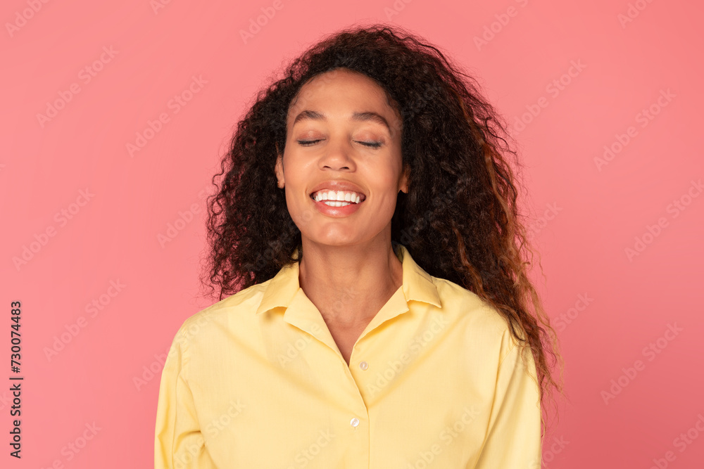 Joyful black woman with closed eyes smiling, posing in yellow shirt Joyful black woman with closed eyes smiling, posing in yellow shirt