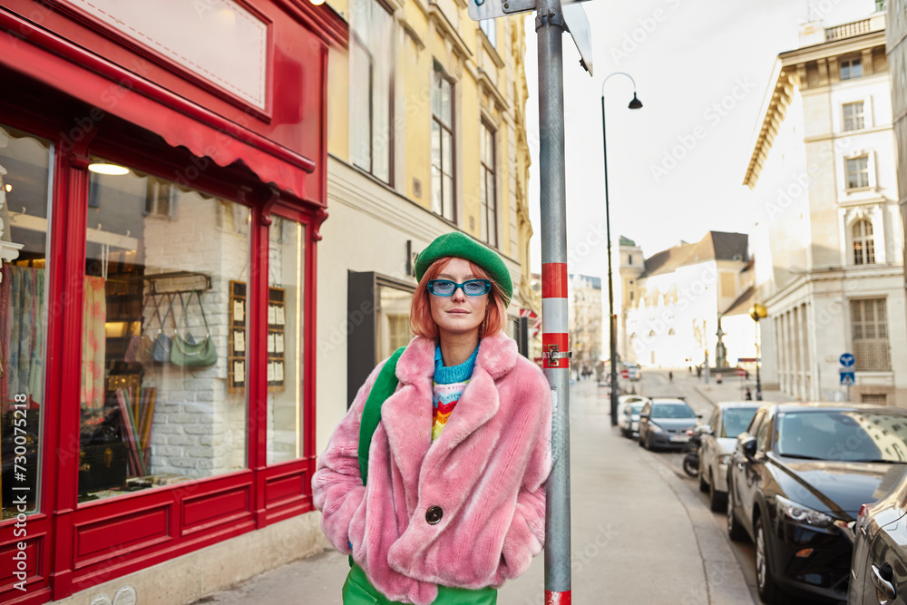 trendy woman in faux fur jacket and sunglasses looking at camera on city street in Vienna, Austria trendy woman in faux fur jacket and sunglasses looking at camera on city street in Vienna, Austria