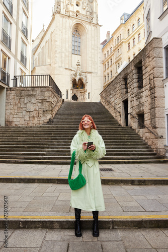urban vibes, happy woman in trendy sunglasses with smartphone walking on city street in Vienna © LIGHTFIELD STUDIOS