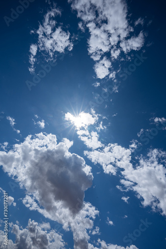 The sun s rays piercing through dense clouds in a blue sky.