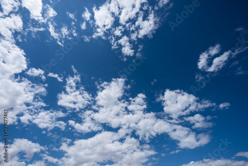 Bright blue sky peppered with fluffy white clouds. © Maria