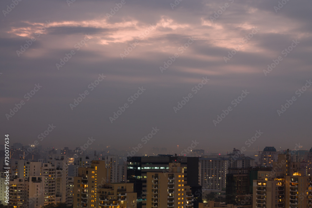 Gurgaon,Haryana,India colorful sunset on a foggy winter evening.Aerial view of Gurugram urban cityscape with modern architecture,commercial ,luxury residential apartment buildings.Delhi NCR.