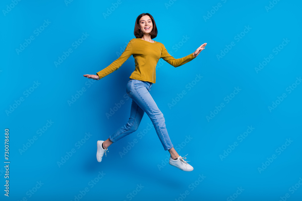 Full length photo of excited sweet lady dressed shirt jumping high running fast empty space isolated blue color background