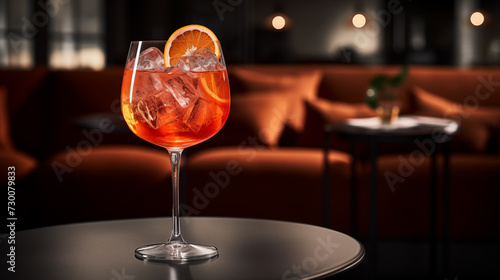 Aperol Spritz in a glass with a low stem on a gray table with a massive leather chair in the background  close-up
