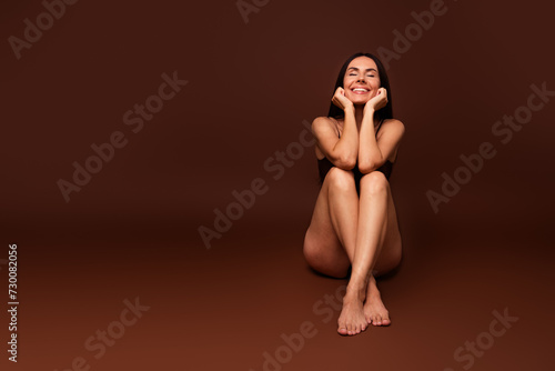 Full length photo no filter of lovely young lady sit floor cute smile posing model wear trendy lingerie isolated on brown color background