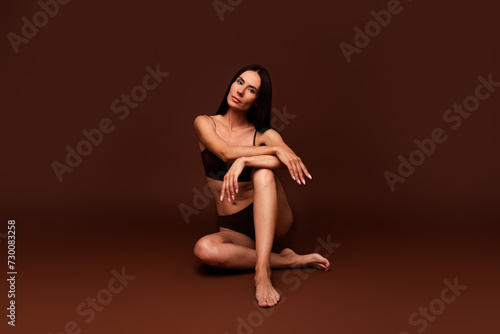 Full length photo no filter of lovely young lady sit floor posing model wear trendy lingerie isolated on brown color background