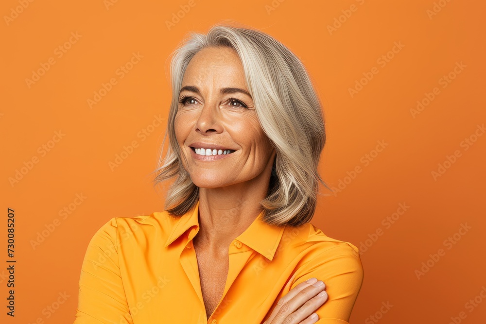 Portrait of smiling mature woman in yellow shirt on orange background. Portrait of smiling mature woman in yellow shirt on orange background.