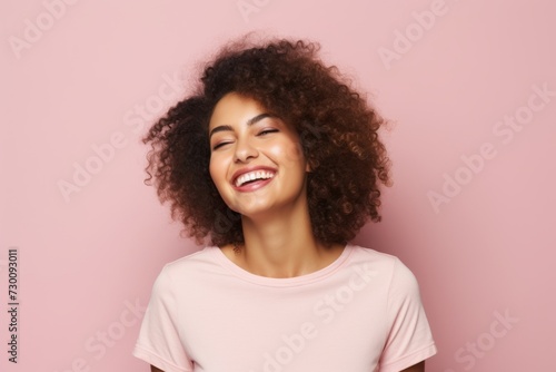 Young african american woman with afro hairstyle smiling on pink background