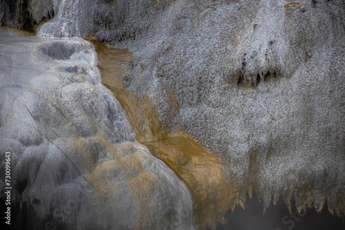 gray and yellow stone texture in rotorua geyser in new zealand with water
