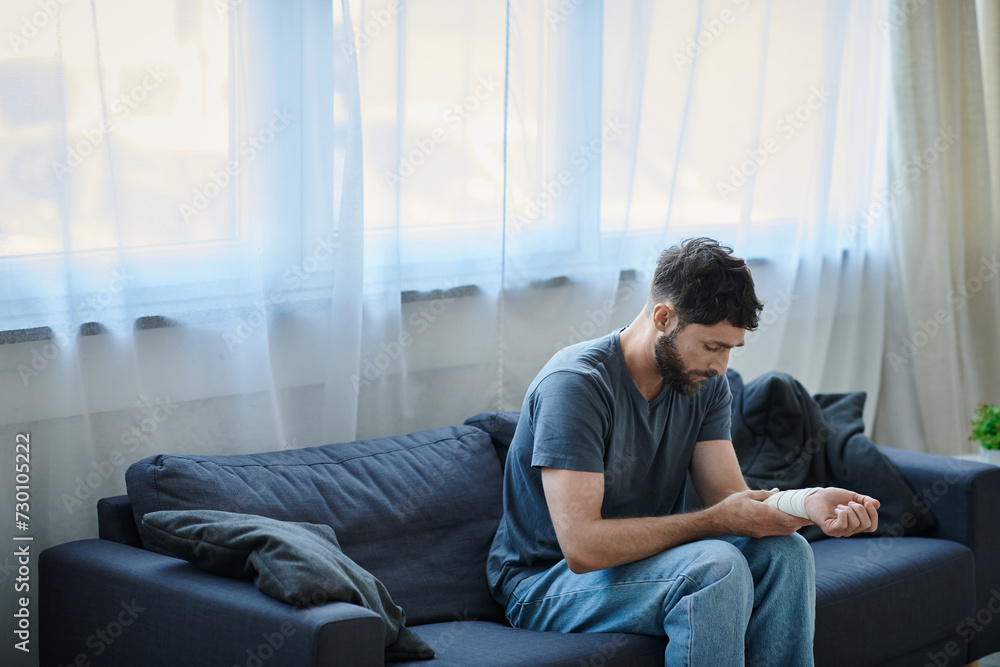 depressed man with bandage on arm after attempting suicide sitting on sofa, mental health awareness depressed man with bandage on arm after attempting suicide sitting on sofa, mental health awareness