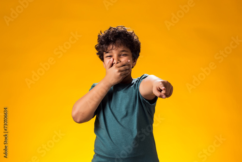 Kid boy laughing at somebody and pointing finger at camera. Bulling concept photo