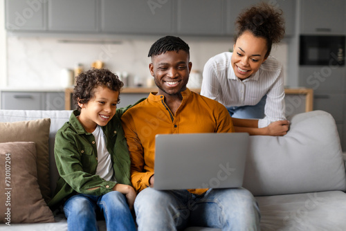 Happy family enjoying time together with laptop at home © Prostock-studio