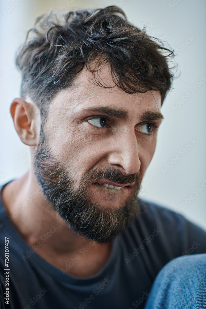 Fototapeta premium ill traumatized man with beard biting his lips during depressive episode, mental health awareness