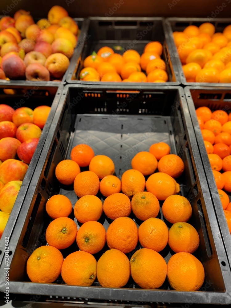 Oranges lying in a plastic crate on a supermarket shelf at the fruit and vegetable department section