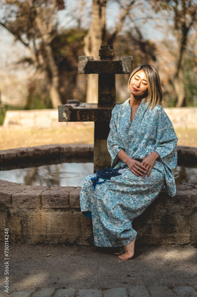 Japanese beauty: asian blonde-haired woman in traditional white silk kimono with leaves design in a japanese garden in a sunny day Japanese beauty: asian blonde-haired woman in traditional white silk kimono with leaves design in a japanese garden in a sunny day