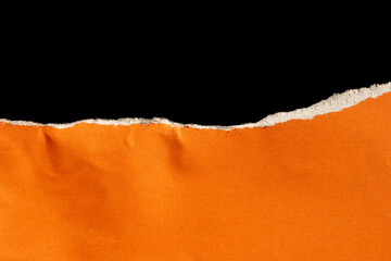 Ripped orange paper isolated on black background. Torn paper with space.