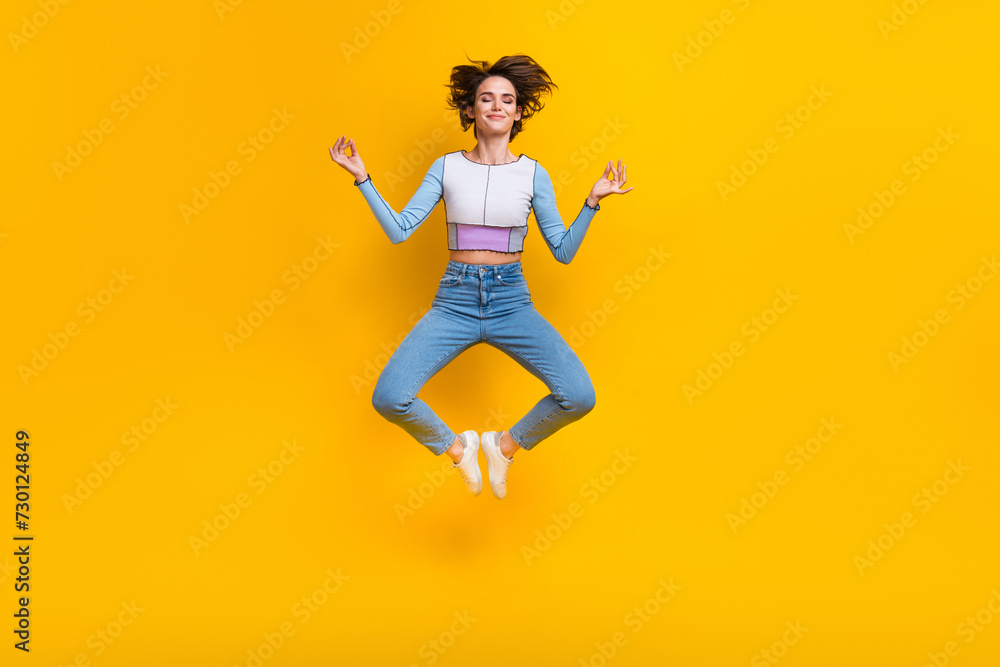 Full length portrait of carefree pretty nice person jump flying meditate isolated on yellow color background