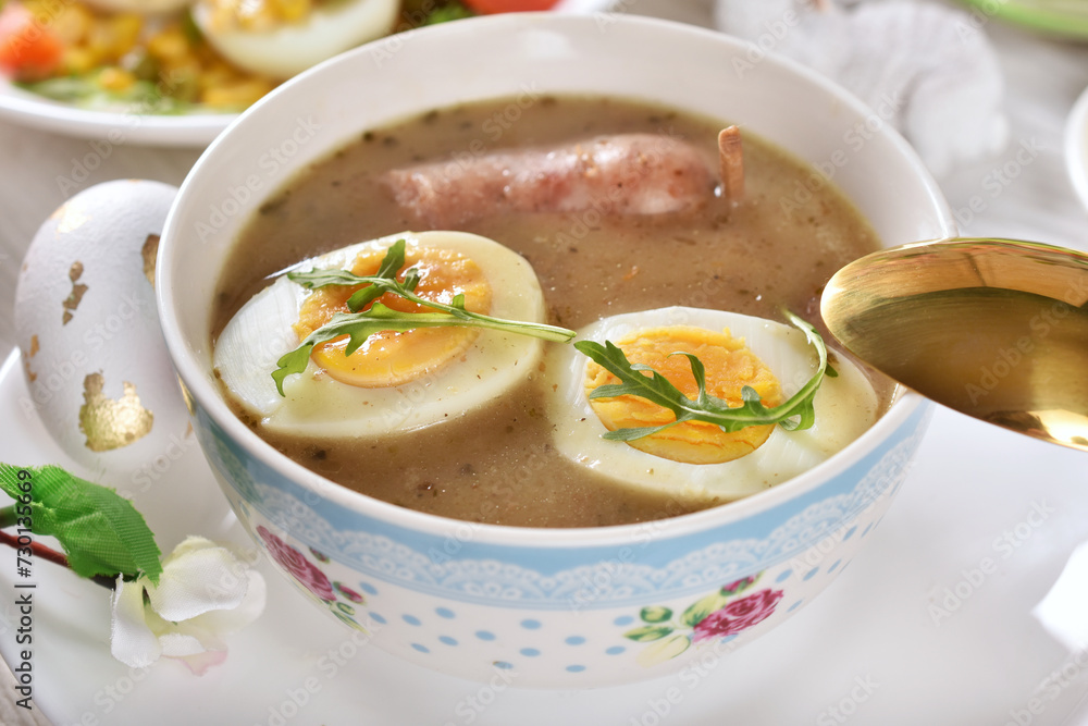 A bowl of traditional Polish white borscht with eggs and sausage on Easter table A bowl of traditional Polish white borscht with eggs and sausage on Easter table