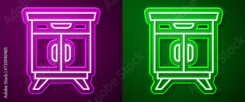 Glowing neon line Furniture nightstand icon isolated on purple and green background. Vector