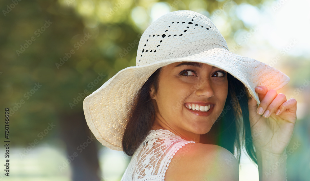 Woman, travel and freedom in park or garden, smile and joy on summer holiday. Female person, peace and enjoy vacation in countryside, outdoors and hat for protection on weekend adventure in nature