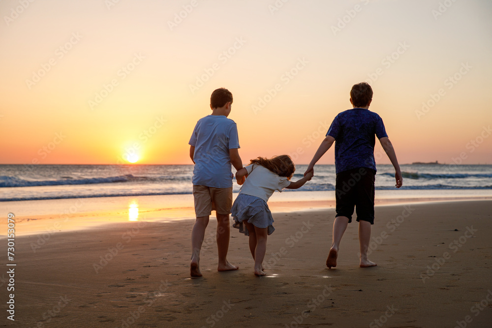 Portrait of three children, happy kids on beach at sunset. happy family, two school boys and one little preschool girl. Siblings having fun together. Bonding and family vacation