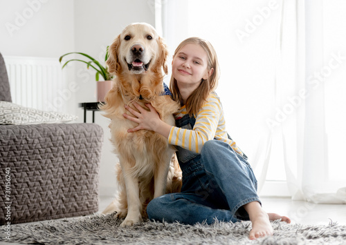 Fototapeta Naklejka Na Ścianę i Meble -  Girl With Golden Retriever Dog Poses At Home On Floor For A Portrait With Dog
