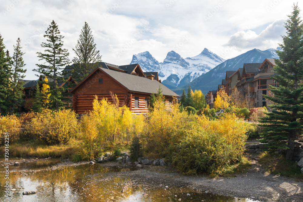 Fototapeta premium Town of Canmore in autumn. Alberta, Canada. Canmore Opera House at Spring Creek. The Three Sisters trio of peaks in the background.