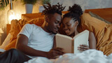 Young calm african loving couple girl guy in white t-shirts reading book lying on bed under blanket indoors in bedroom at home spending time in room. Rest relax good mood quarantine lifestyle concept.