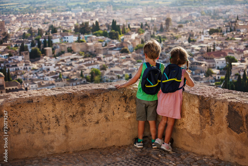 Cute siblings standing on viewpoint admire view of Granada