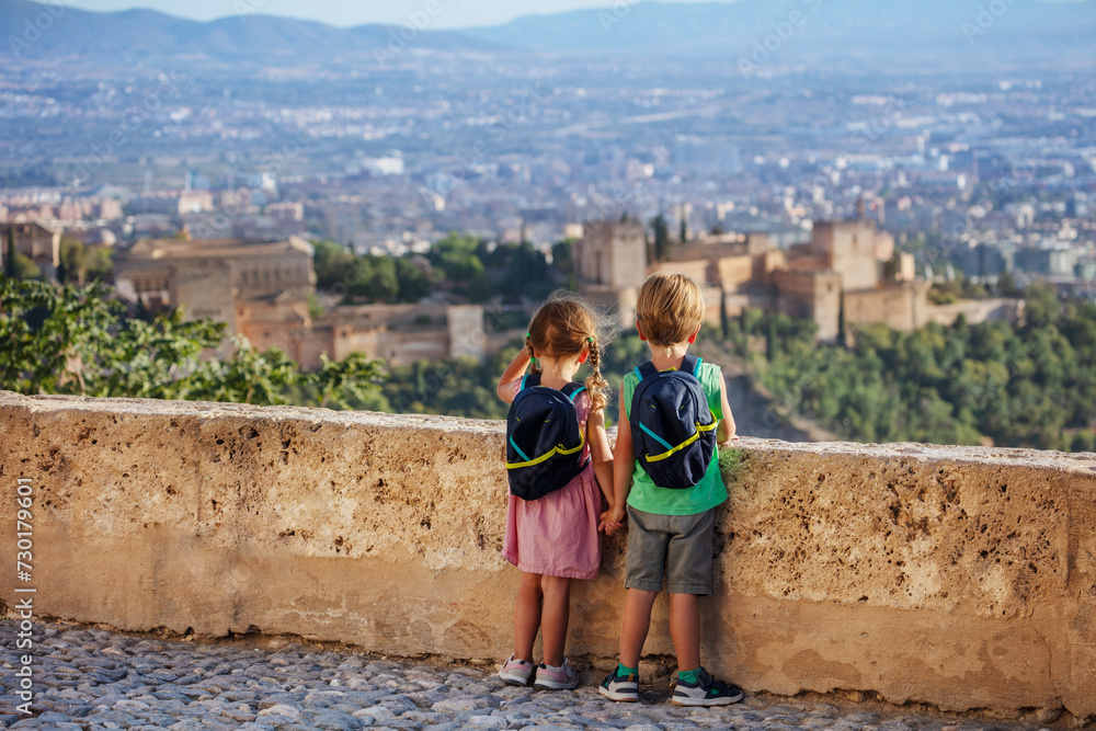 Fototapeta premium Cute boy and girl overlook magnificent castle Alhambra, Spain