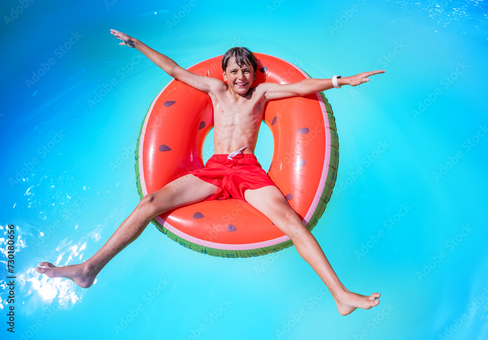 Young swimmer relax on big inflatable ring, in star shape pose - obrazy, fototapety, plakaty 