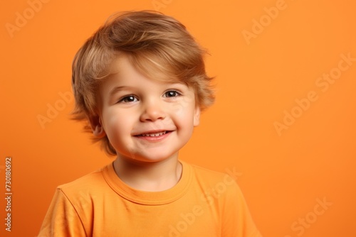 Portrait of a cute smiling little boy on a orange background.
