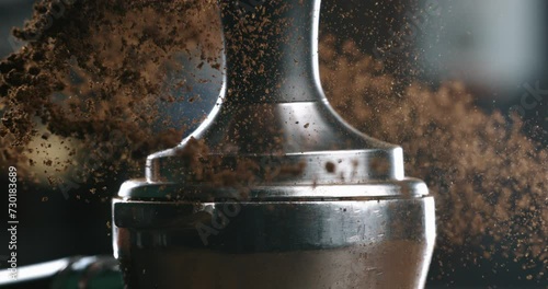 Super slow motion macro of barista preparing espresso with portafilter and tamper with fresh flavorful aromatic roasted ground coffee powder at 1000 fps in cafeteria for serving it to customer.