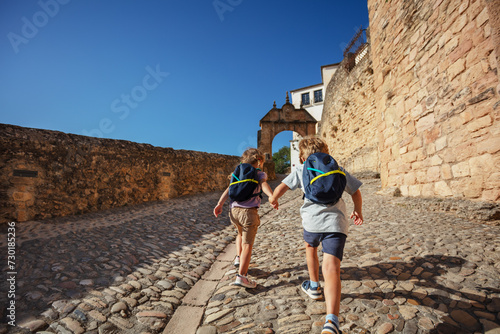 Two kids with backpacks running in walls of old Ronda, Spain
