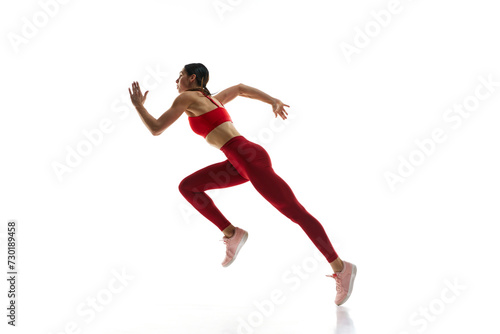 Competitive, concentrated young woman, runner athlete training, running against white studio background. Concept of sport, active and healthy lifestyle, sportswear, competition