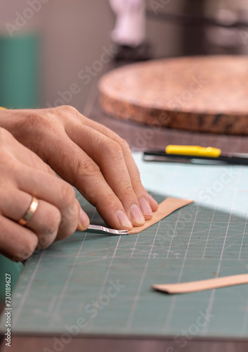 A leather craftsman is making a watch strap. 