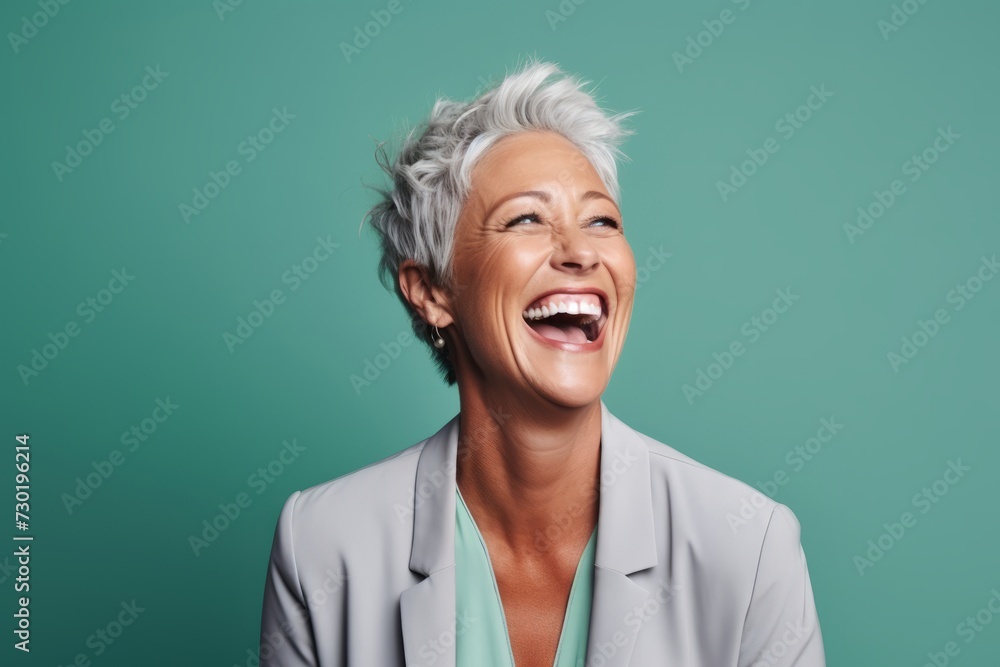 Portrait of a happy senior business woman laughing against a green background