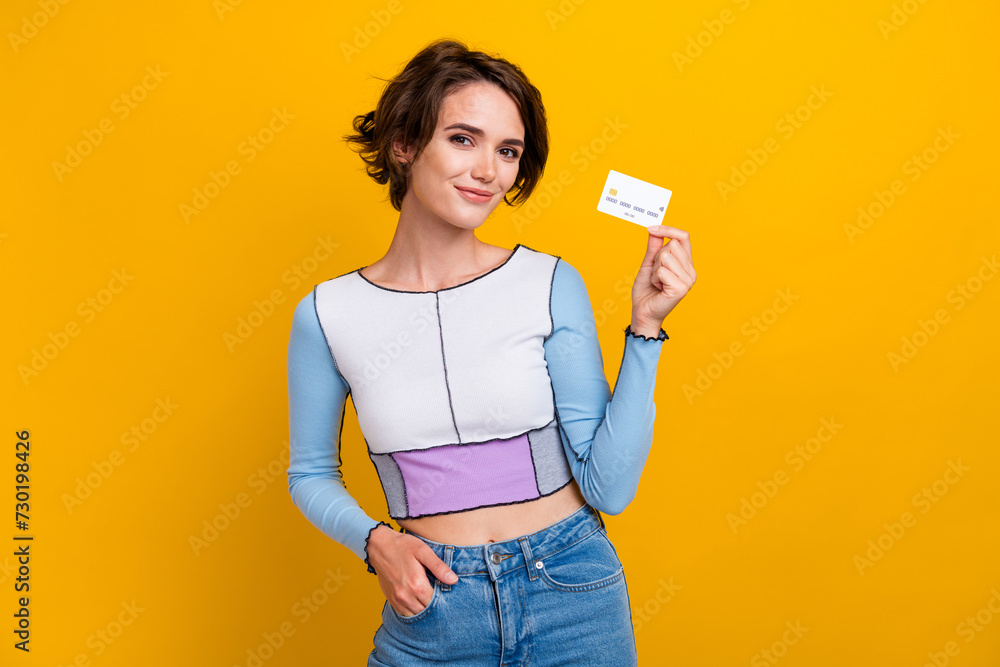 Photo of adorable shiny woman wear top rising credit card smiling isolated yellow color background Photo of adorable shiny woman wear top rising credit card smiling isolated yellow color background
