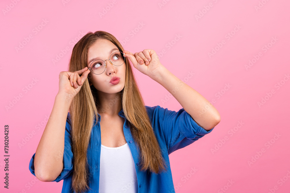Photo of suspicious unsure girl wear blue shirt arms spectacles looking empty space isolated pink color background Photo of suspicious unsure girl wear blue shirt arms spectacles looking empty space isolated pink color background