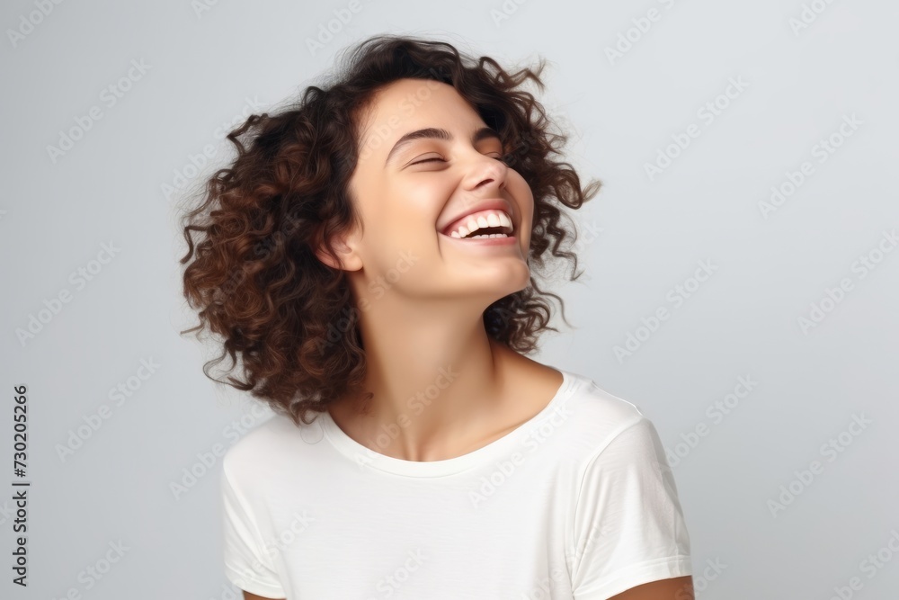 Portrait of a happy young woman laughing and looking up over grey background Portrait of a happy young woman laughing and looking up over grey background